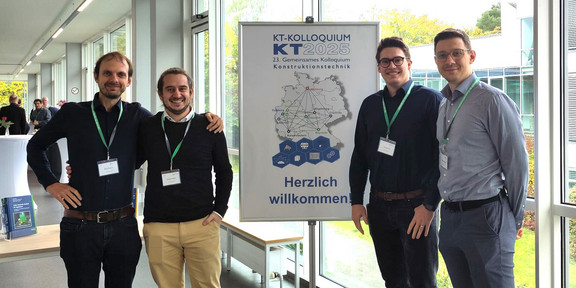 Vier Mitarbeiter des LKP stehen vor einem Plakat