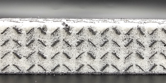 Dargestellt ist ein Querschnitt eines Schaumblock. Der Block besteht aus einer 3D-gedruckten Füllstruktur, die mit Schaum ausgefüllt wurde.